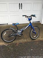 Full side view of the blue Trek kids' bike on a concrete surface showing the entire frame, wheels, seat, chain guard and handlebars.