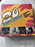 Top view of the "20 Explosive Original Hits Original Stars" LP record cover with colorful design and band photos, edges showing minor wear.