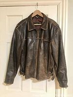 Front view of the brown leather jacket hung on a hanger showing full front and zipper closure.