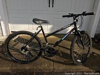 Side view of black Huffy mountain bike showing frame, tires, seat, pedals, and gear system.