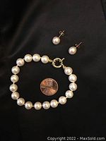 Photo showing pearl bracelet with 14 carat gold toggle clasp and matching pearl stud earrings with gold posts next to a US penny for size reference.