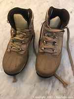 Pair of Timberland boys' winter boots showing top and front views with laces tied and untied placed on marble surface.