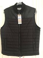 Front view of Kenneth Cole men's vest hanging on hanger, black quilted body with solid upper chest panel.