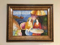Framed watercolor painting showing the two women at table and coastal scene background.