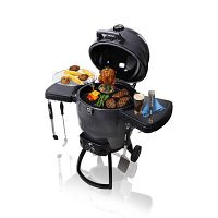 Charcoal kamado-style grill with lid open, cooking meats and vegetables on cast iron grate and chrome secondary rack, side shelves extended