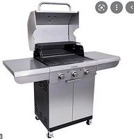 Front-angle view of the stainless steel Saber Select grill with lid open, showing cooking grates and side shelves