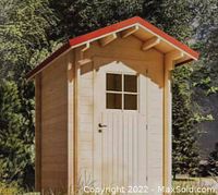Front view of unassembled pine shed with door closed and red pitched roof
