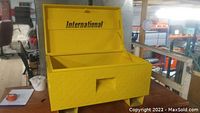 Front view of open yellow steel job box in warehouse setting