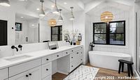Modern bathroom interior design featuring white cabinetry, freestanding tub and pendant lighting