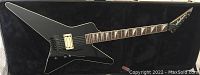 Black Explorer-style electric guitar with white binding, Floyd Rose tremolo