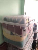 Closed plastic bin packed with various blankets and throws visible through translucent lid.