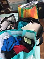 Four bags shown containing various mens sports clothing, women's hats, and footwear.