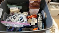 Bin containing cords, remote controls, power strip, and Bragi headphones box