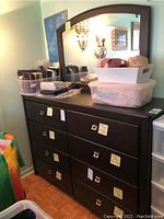 Front view of wood dresser with eight drawers and attached mirror, showing dark wood finish and metal drawer pulls. Some personal items on top not included with sale.
