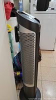 Side view of the black and silver tower fan showing the perforated grill and overall design.