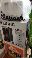 Photo of boxed Keurig K35 coffee maker and boxed GE fan heater stacked together