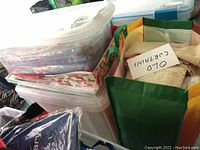 Two plastic storage bins and one reusable bag labeled 'OLD CURTAINS' filled with textiles and linens.