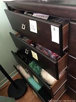 Four wooden drawers with labels indicating contents: socks, scarves, wraps, and knit shawls