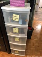 Full view of the five-drawer white plastic storage container showing labels on drawers for miscellaneous accessories, travel, sewing, and other contents inside.