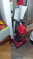 Full view of the Dirt Devil Featherlite upright vacuum cleaner with attached cleaning tools and extension wand, showing overall condition and accessories.