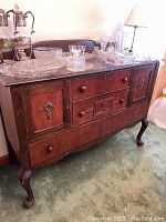 Full view of the antique wooden buffet cabinet with various glass and metal items on top (items not included).