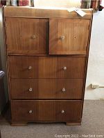 Front view of Deco style wooden chest showing two cabinet doors on top and three drawers below with clear round knobs.
