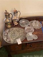 Frontal view of the entire set showing the various glassware pieces on a wooden cabinet