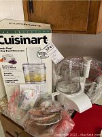 Photo showing full lot including Cuisinart box, main food processor base, accessories in sealed plastic bags, and instruction manual.