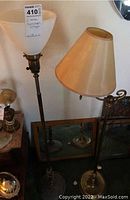 Two metal floor lamps approximately 54 inches tall; one with frosted ribbed glass shade, the other with beige fabric shade and swing arm.