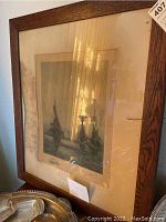 Framed print of large ships in wooden frame with glass and matting, some reflections visible.