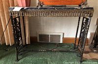 Full front view of table showing black marble top and wrought iron base