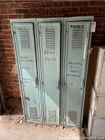 Front view of three metal lockers with handwritten labels for organized storage.