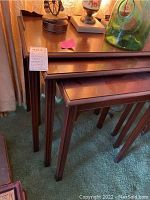 Set of three mahogany nesting tables stacked together showing front corner and tapered legs.