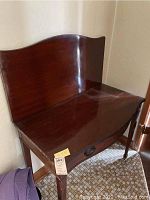 Sheraton style table with curved backboard and worn finish.