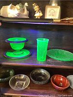 Overall display under UV light showing uranium glass items alongside ceramic figurines and pressed glass bowls