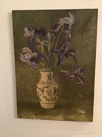 Front view of oil painting showing blue iris flowers in vase with olive green background