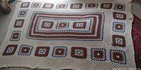 Full view of large crocheted blanket laid flat, showing pattern layout and color.