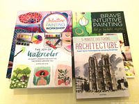 Photo showing four art books stacked, with visible titles and colorful covers.