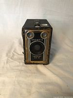 Front view of the Kodak Brownie Target Six-16 camera showing lens, two viewfinder windows, and decorative plate.