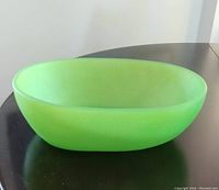 Bright green oval resin bowl on dark table