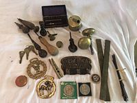 Wide view of all brass items and Queen's Jubilee Medals showing variety of shapes including medallions, keys, strips, tools, plaques, and boxed shafts.