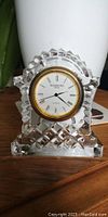 Front view of Waterford Crystal carriage clock showing clear cut crystal and gold rim around white clock face with Roman numerals.