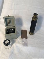 Photo showing all items: brass and leather spyglass, wooden box, 3 magnifiers including one in a folded tan case.