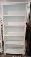 Full front view of white bookshelf showing total of five shelves.