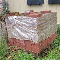 First photo showing a shrink-wrapped pallet of red bricks stacked neatly outdoors, bricks measuring 5x7 inches.