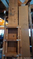 Photo showing a chip board sheet, a maple board, and some wood furniture items including headboard and ladder frames stacked together.