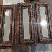 Three wooden framed mirrors with dragonfly designs laid flat, showing front reflective side and frame detail
