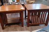 Two square oak end tables side by side on floor, showing top surfaces and side details.