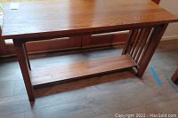 Full front view of oak entryway table showing tabletop, legs, lower shelf, and slatted side panels