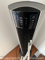 Close-up of black tower stand fan control panel showing power button, timer options, and speed settings.